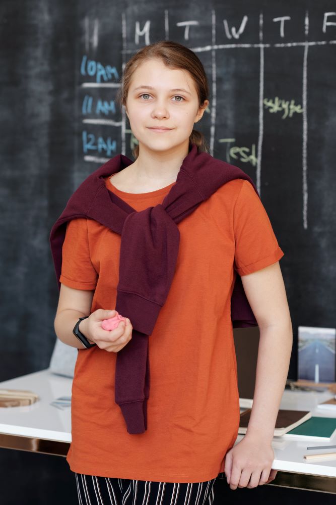 Teenage girl - Photo by Julia M Cameron: https://www.pexels.com/photo/girl-in-orange-shirt-smiling-while-holding-pink-kinetic-sand-4144456/