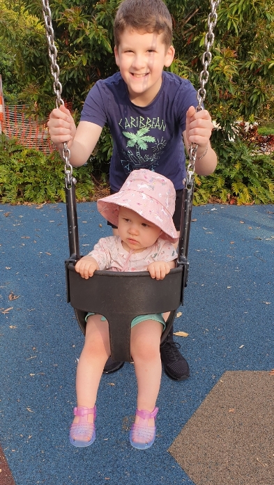 Roman pushing his baby sister on a swing