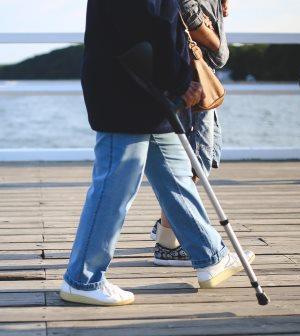 adult walking on pier with elbow crutch