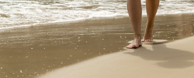 feet of man walking on the beach