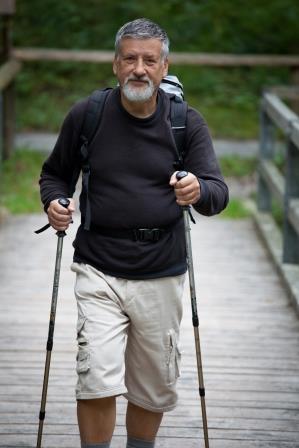 senior man walking with poles and a backpack