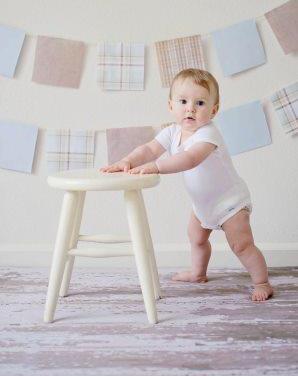 baby standing and holding onto stool