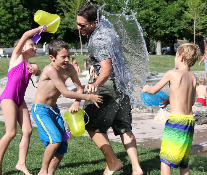 children and father playing with buckets of water